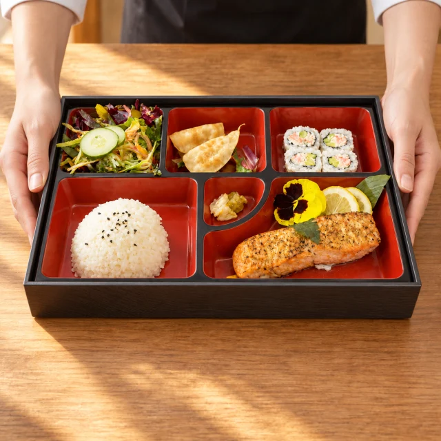 Hands gently setting the salmon bento on the table